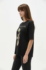 Remera blanca de algodón de manga corta, con cuello redondo y corte holgado. Presenta estampado frontal de un lazo con detalles de brillos y la frase 'Made of sweetness'.