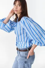 Camisa de manga larga abullonada con diseño a rayas verticales celestes y azules, cuello mao y cierre frontal con botones ocultos.