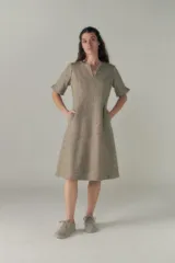 Vestido a la rodilla color beige, con escote en V, mangas cortas con detalle de tajo, bolsillos laterales y forro interior.