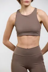 Top deportivo de compresión media con escote redondo, diseño al cuerpo y espalda abierta. Cuenta con elástico interno en la cintura para mayor sujeción.