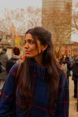 Sweater oversize de lana natural con estampado cuadrillé en tonos azul, verde y rojo. Presenta cuello alto, mangas largas y detalles de flecos torneados en el cuello, puños y dobladillo.