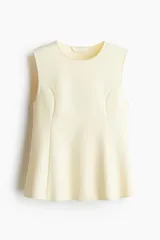 Musculosa sin mangas color amarillo pálido, con cuello redondo y paneles laterales que crean un efecto moldeador y un ruedo con peplum acampanado.