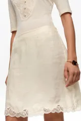 Falda mini de corte recto color blanco, con detalle de encaje en el bajo y cintura elástica.