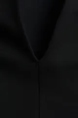 Top de manga larga negro, confeccionado en tejido con textura efecto neopreno. Presenta escote redondo al frente y escote en V pronunciado en la espalda. El calce es entallado en la cintura con un bajo levemente acampanado.