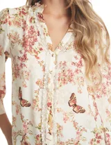 Blusa de gasa con estampado floral y de mariposas, color beige. Presenta cuello a la base fruncido, escote en V con aplique de puntilla vertical en la parte delantera y cierre central con botones forrados. Posee mangas tres cuartos con puños abotonados.