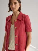 Chaqueta de lino color negro con costuras a contratono, mangas cortas con dobladillo y detalle de franja texturizada en la cintura. Presenta cuello camisero y etiqueta de cuero en la espalda.