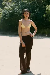 Falda pantalón de tiro alto en color marrón oscuro, con diseño superpuesto que combina una falda envolvente con lazadas laterales y un pantalón de corte recto debajo. Cuenta con cierre lateral oculto.