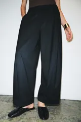Pantalón de tiro medio con corte wide leg y cintura elástica ajustable. Presenta bolsillos laterales ocultos en las costuras y un diseño de pierna ancha con caída fluida.