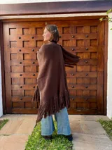 Ruana tejida en color chocolate, confeccionada en lana, con diseño de textura lisa y terminaciones con flecos largos en los extremos.