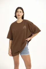 Remera marrón con cuello redondo, corte holgado y estampado pequeño de flores y texto en el pecho.