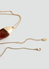 Collar largo de cadena fina dorada con un dije colgante en forma de gota, combinación de metal dorado y resina en tono ámbar.