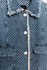 Chaqueta de denim de corte clásico con textura perforada, cuello solapa, bolsillos delanteros de plastrón, cierre frontal con botones a contraste y detalles de flecos en los bordes.