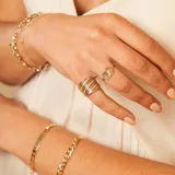 Anillo de oro 9k con diseño de grecas y una hilera central de circonias brillantes.