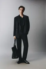 Pantalón de traje negro de corte regular fit, con pinzas delanteras, bolsillos laterales y cierre frontal con cremallera y botón.