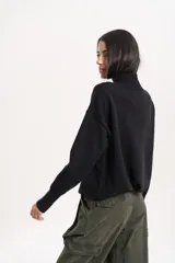 Polera de lana de corte holgado, con cuello alto tejido y mangas largas con caída de hombro.