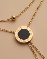 Collar doble de acero con baño de oro, con diseño reversible en nácar y ónix, compuesto por dos cadenas con dijes circulares y detalles de esferas.