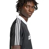 Remera de estilo retro inspirada en el fútbol, color negro con cuello polo blanco en diseño en V. Presenta las icónicas tres tiras blancas en las mangas y el logo del trifolio en el pecho.