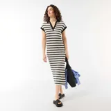 Vestido largo de punto a rayas horizontales blancas y negras, con mangas cortas, cuello tipo polo negro y escote en V.