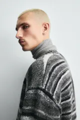 Cárdigan de punto con diseño de rayas horizontales en tonos grises y negros. Presenta un corte relajado, cuello en pico, cierre frontal con botones y acabados en rib en puños y bajo.