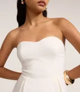 Vestido corto strapless color verde esmeralda, con escote corazón y falda acampanada con pliegues.