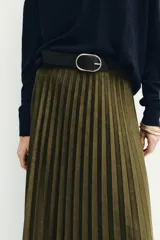 Falda midi de tiro alto en tejido plisado color verde oliva. Presenta un cinturón negro a contraste con hebilla metálica dorada y cierre lateral con cremallera oculta.