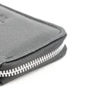 Billetera compacta de cuero vacuno color negro, con cierre perimetral y logo grabado en el frente.