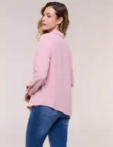 Blusa verde de calce holgado y caída fluida, confeccionada en tejido tipo crepé. Cuenta con cuello camisero con solapa, escote en V y cierre parcial al frente con tres botones metálicos. Las mangas son largas con puños abotonados.