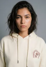 Buzo con capucha color crudo, de corte holgado y manga larga, con bolsillo canguro frontal.