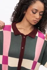 Saco largo de punto con diseño geométrico de cuadros en tonos verde, rosa y crema. Presenta cuello tipo polo, cierre frontal con botones y puños en color bordó.