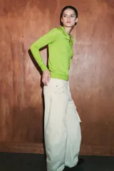 Jersey polo de punto fino color verde lima, confeccionado con lana. Presenta cuello polo, manga larga y botones delanteros.