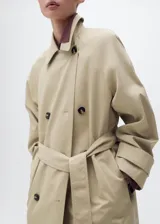 Trench coat de corte recto y diseño oversize, con cierre de doble botonadura, cuello de solapa ancha, bolsillos laterales y mangas largas con puños abotonados. Incluye cinturón desmontable y forro interior.