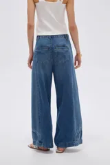 Pantalón jean azul de tiro alto, corte baggy y piernas anchas, con costuras decorativas frontales.
