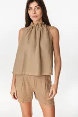 Blusa de lino color beige, de corte en línea A y escote halter con frunces y volado en el cuello.