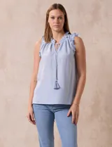 Blusa sin mangas con estampado a rayas verticales celestes y blancas. Tiene cuello redondo fruncido con escote en V y lazo con borla.