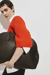 Top de punto acanalado color naranja, con cuello redondo, mangas al codo de corte raglán y diseño oversized. Presenta terminaciones acanaladas en cuello, puños y bajo.