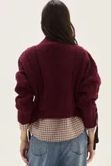 Polera de tejido de punto con diseño de ochos y detalles de tientos en contratono en las mangas. Presenta cuello alto y corte cropped.