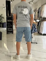 Remera gris melange de manga corta y corte clásico, con estampa en la espalda que dice "Wildest in the club" junto a un gráfico de un disco compacto.