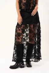 Pollera larga de encaje negro con silueta fluida y diseño asimétrico. Presenta un forro interno hasta la altura del frunce, dejando la parte inferior con transparencias que aportan movimiento.