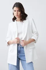 Blazer de corte recto y diseño minimalista, color blanco, con solapas clásicas, bolsillos frontales con solapa y mangas tres cuartos con detalle de botones.