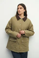 Campera color verde militar con cuello de pana marrón, bolsillos con solapa y botones metálicos. Interior forrado con tela satinada capitoneada.