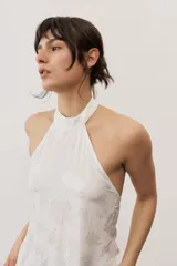 Top halter celeste con diseño asimétrico de corte más largo en la parte trasera, cuello alto y sutil estampado floral.