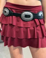 Cinturón de cuero sintético negro con hebilla central grande y apliques metálicos decorativos de estilo western.