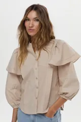 Camisa de algodón a rayas color beige y blanco, con cuello mao, volados en los hombros, mangas abullonadas y nudo frontal en el dobladillo.