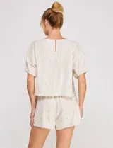 Blusa corta de lino y viscosa color beige, con bordado de grandes flores al tono, cuello redondo, mangas cortas abullonadas y corte holgado.