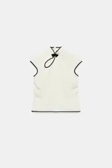 Top de cuello mao con detalle de alamar y cierre frontal con nudo decorativo. Diseño de manga corta, color blanco con ribetes negros en contraste.