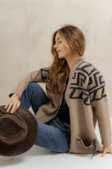 Saco tejido de punto con diseño de guarda inca en la parte superior. Presenta bolsillos frontales con detalles de tiras de cuero y flecos. De corte recto y largo medio, con terminaciones en tejido acanalado.