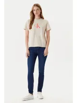 Remera color crema de algodón, con cuello redondo y logo de Calvin Klein estampado en color coral en el pecho.