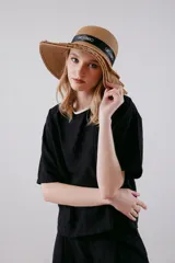 Blusa color beige de viscosa texturizada, con cuello redondo con detalle de sesgo a contratono negro, espalda con escote gota y lazo.