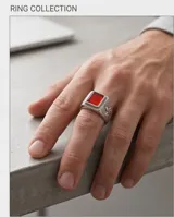 Anillo de acero tipo sello con piedra central rectangular de color rojo y diseño grabado en los laterales.