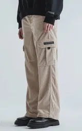 Pantalón cargo de corderoy color beige claro, de calce regular y pierna ancha, con múltiples bolsillos cargo laterales y etiqueta negra en uno de ellos.